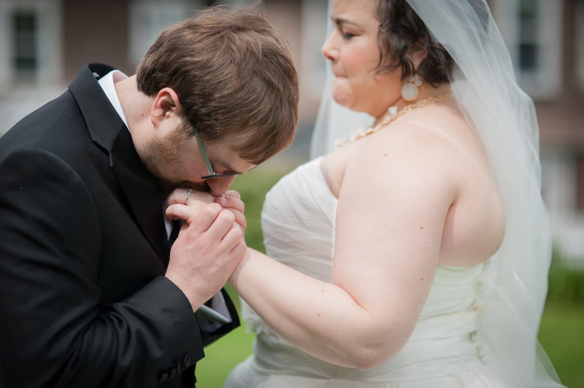 groom kissing brides hand in an emotional moment