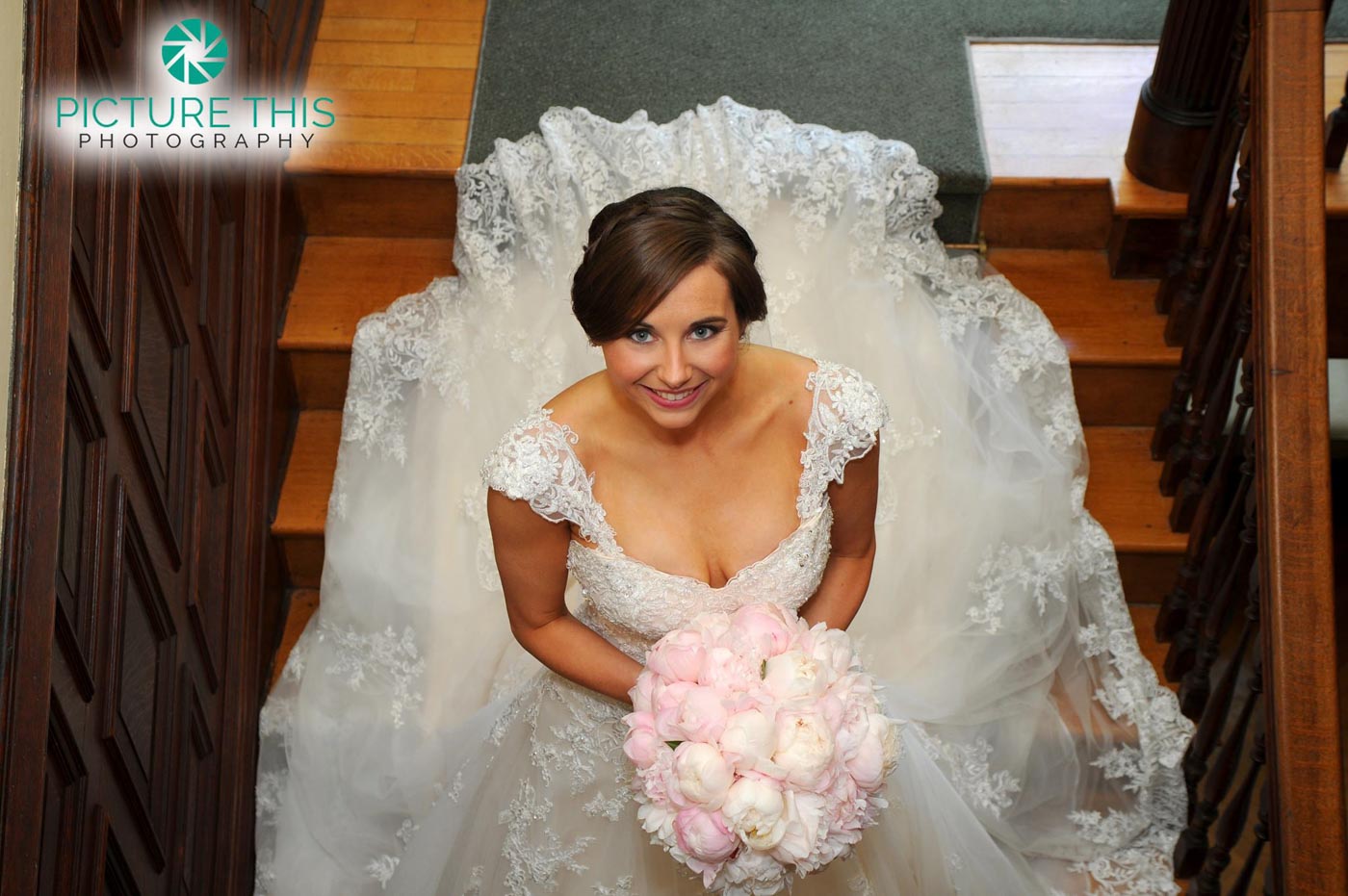 alumni-bride-looking-up-to-landing-with-gown-flowing-around-stairs