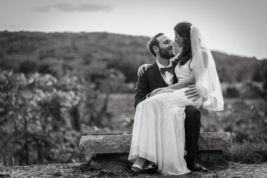 bride sitting on grooms lap overlooking hayfields